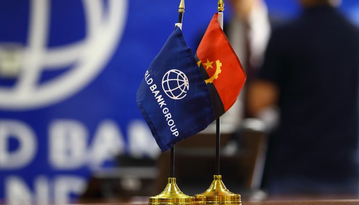Bandeiras do Banco Mundial e de Angola, sob o fundo da instituição...